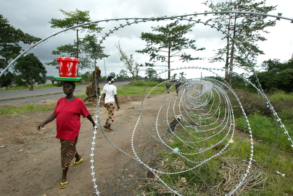 People carrying food stuffs walk past a checkpoint close to the Po river in rebel territory, near Monrovia, Liberia