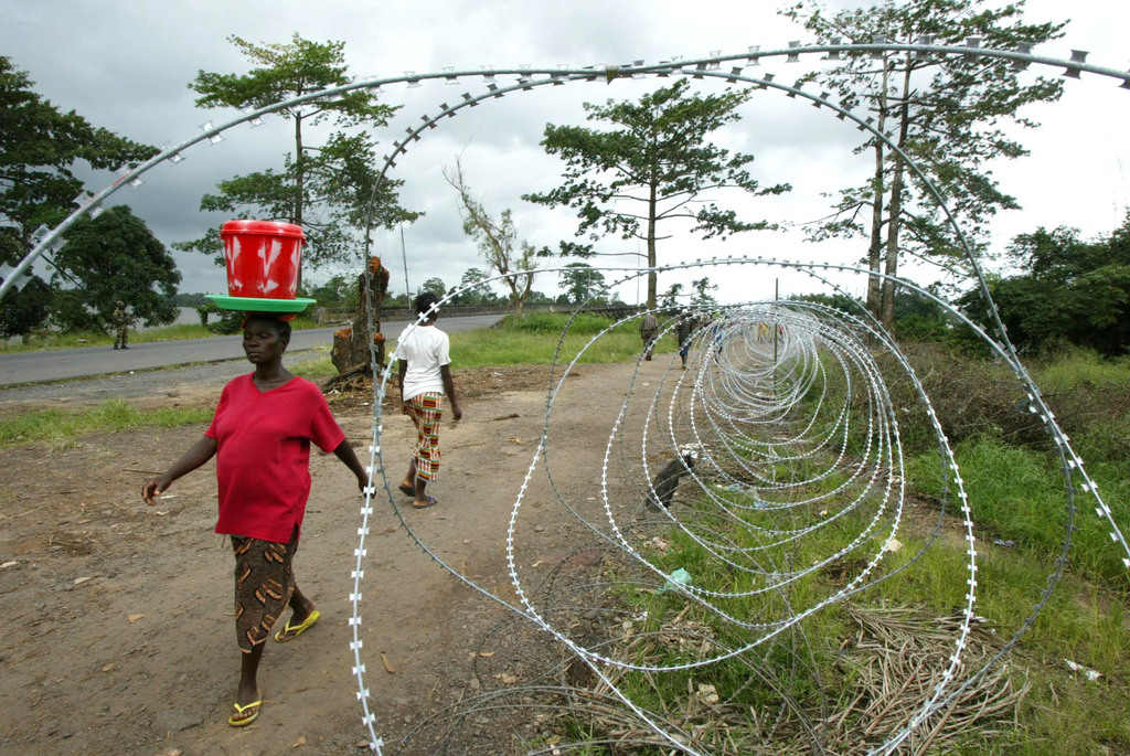 People carrying food stuffs walk past a checkpoint